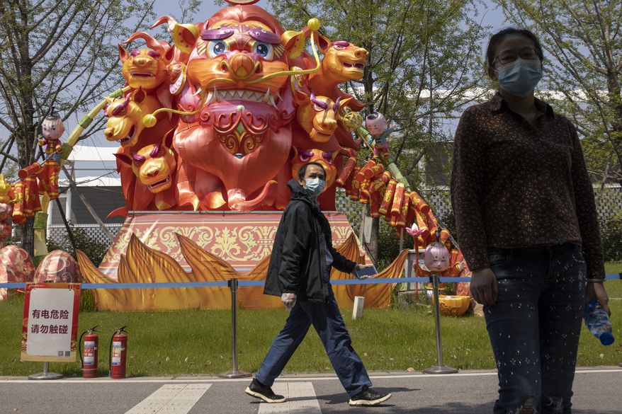 Residents wearing masks against the coronavirus walk past lantern sculptures at a park in Wuhan in central China's Hubei province on Thursday, April 9, 2020. Chinese authorities ended the lockdown of Wuhan on Wednesday, allowing people to move about and leave the city for the first time in 76 days. (AP Photo/Ng Han Guan)