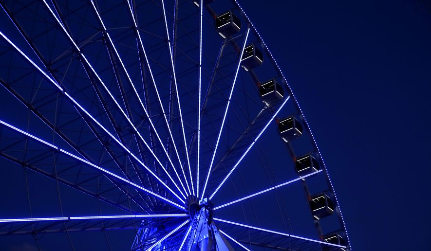 Blue LED lights light up a Ferris wheel outside Union Station, Thursday, April 9, 2020, in St. Louis. Lights on various buildings, attractions and streetlights have been changed to blue to recognize law enforcement, health care workers and other essential personnel working during the coronavirus outbreak. (AP Photo/Jeff Roberson)