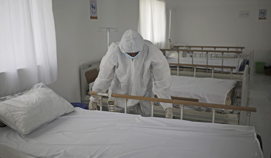 A medical staff member adjusts the sheets on a bed as personnel setup a coronavirus quarantine ward at a hospital in Sanaa, Yemen, Sunday, March 15, 2020. (AP Photo/Hani Mohammed)