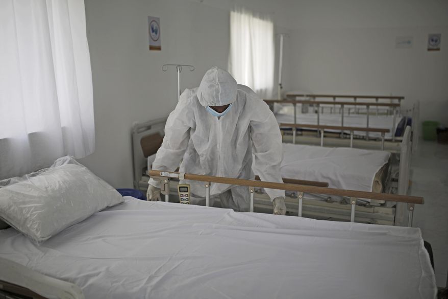 A medical staff member adjusts the sheets on a bed as personnel setup a coronavirus quarantine ward at a hospital in Sanaa, Yemen, Sunday, March 15, 2020. (AP Photo/Hani Mohammed)