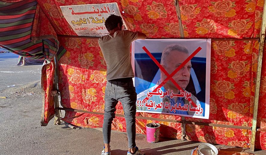 A poster with a defaced picture of Mustafa Kadhimi, Iraq&#39;s intelligence chief and new prime minister-designate, is pictured in Tahrir Square, Baghdad, Iraq, Saturday, April 11, 2020. The Arabic sentence on the poster reads &quot;an American citizen is the head of the Iraqi intelligence.&quot;(AP Photo/Khalid Mohammed)