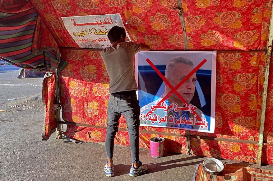 A poster with a defaced picture of Mustafa Kadhimi, Iraq&#39;s intelligence chief and new prime minister-designate, is pictured in Tahrir Square, Baghdad, Iraq, Saturday, April 11, 2020. The Arabic sentence on the poster reads &quot;an American citizen is the head of the Iraqi intelligence.&quot;(AP Photo/Khalid Mohammed)