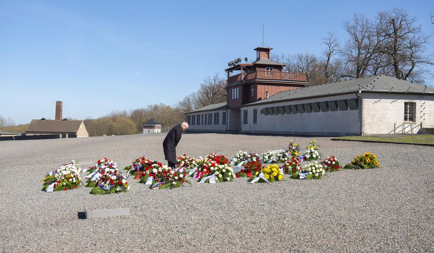 Volkhard Knigge, foundation director of the Nazi concentration camp Buchenwald memorial place, lays down a flower during a minute's of silence in memory of the victims at the 75th anniversary of the liberation of the former Nazi concentration camp Buchenwald by the US Army near Weimar, Germany, Saturday, April 11, 2020. Because of Corona crisis, the memorial is currently closed and all commemoration ceremonies with survivors have been cancelled. For most people, the new coronavirus causes only mild or moderate symptoms, such as fever and cough. For some, especially older adults and people with existing health problems, it can cause more severe illness, including pneumonia. (AP Photo/Jens Meyer)