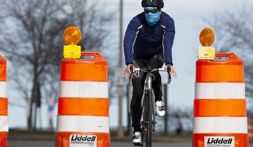 A man rides a bicycle on Day Boulevard which has been closed to traffic to reduce crowding on the adjacent sidewalk and allow social distancing, Saturday, April 11, 2020, in Boston. (AP Photo/Michael Dwyer)
