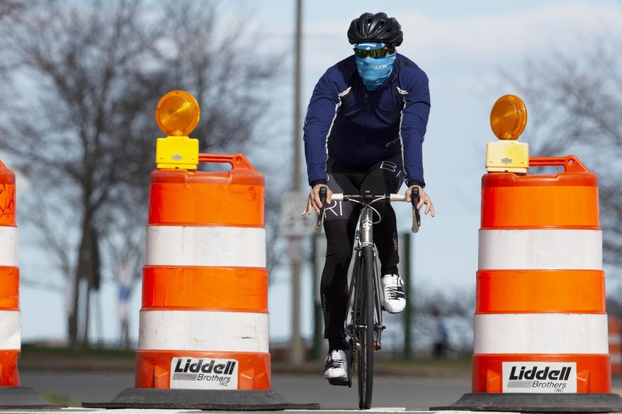 A man rides a bicycle on Day Boulevard which has been closed to traffic to reduce crowding on the adjacent sidewalk and allow social distancing, Saturday, April 11, 2020, in Boston. (AP Photo/Michael Dwyer)