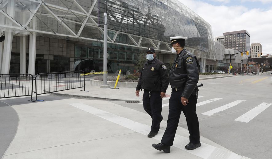 In this April 10, 2020, photo, Detroit Police Capt. Jevon Johnson, right, talks with Lt. Pride Henry outside the TCF Center, in Detroit. The coronavirus pandemic that has crippled big-box retailers and mom and pop shops worldwide may be making a dent in illicit business, too. (AP Photo/Carlos Osorio)