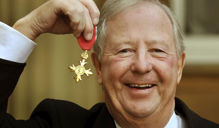 FILE - In this Nov. 28, 2011 file photo, Tim Brooke-Taylor holds his OBE after being presented it by Queen Elizabeth, outside Buckingham Palace in London. British comedian Tim Brooke-Taylor, a member of comedy trio The Goodies, has died after contracting the new coronavirus. He was 79. Brooke-Taylor’s agent says he died Sunday, April 12, 2020 “from COVID-19.”(John Stillwell/PA via AP)