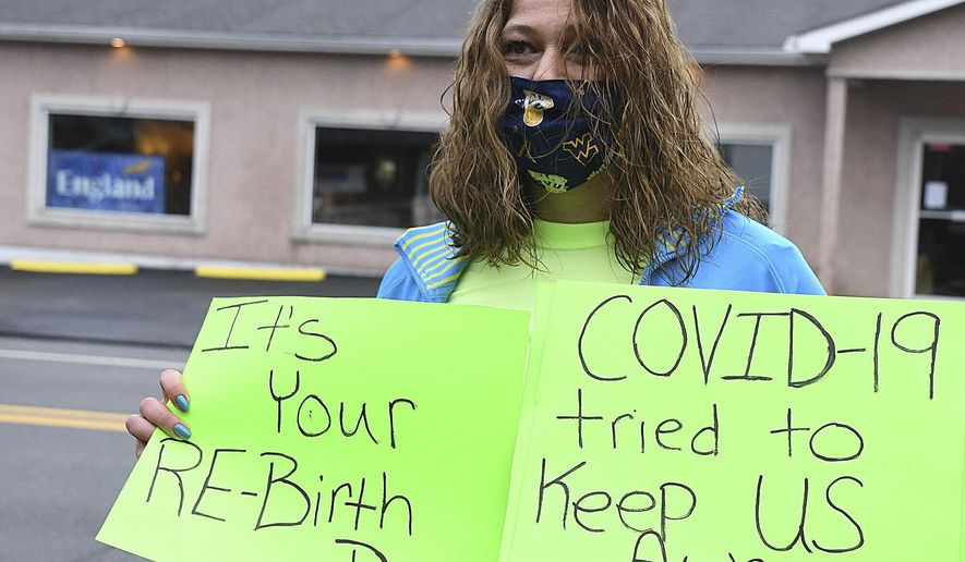 Shannon Barbero displays a message for her mom, Tammy Evans, in front of her mom's house, Wednesday, April 8, 2020, in Beckley, W.Va. Family and friends celebrated with a parade of 14 cars and two fire trucks, the 1-year anniversary of Barbero donating half of her liver to save her mother's life. Evans suffered from nonalcoholic steatohepatitis. (Rick Barbero/The Register-Herald via AP)