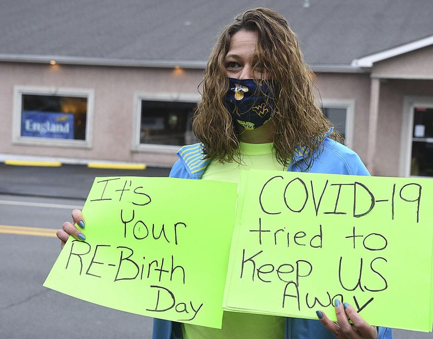 Shannon Barbero displays a message for her mom, Tammy Evans, in front of her mom's house, Wednesday, April 8, 2020, in Beckley, W.Va. Family and friends celebrated with a parade of 14 cars and two fire trucks, the 1-year anniversary of Barbero donating half of her liver to save her mother's life. Evans suffered from nonalcoholic steatohepatitis. (Rick Barbero/The Register-Herald via AP)