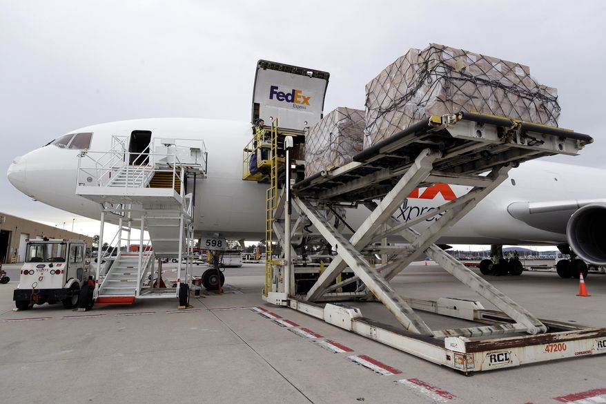 Pallets containing personal protective equipment, top right, are unloaded from a FedEx cargo plane, Sunday, April 12, 2020, at Manchester-Boston Regional Airport, in Manchester, N.H. The cargo plane, carrying about 91,000 pounds of personal protective equipment, which is helpful in preventing the spread of the coronavirus, arrived at the airport in Manchester from Shanghai, China, after passing through United States Customs in Anchorage, Alaska early Sunday, April 12. (AP Photo/Steven Senne)