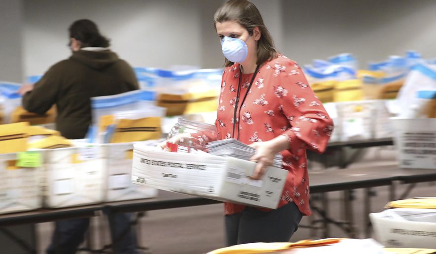 Claire Woodall-Vogg, a business systems administrator with the City of Milwaukee Election Commission carries a basket of ballots as City of Milwaukee Election Commission workers were processing absentee ballots on the fourth floor of an office building at 501 W. Michigan Ave. in Milwaukee on Monday, April 13, 2020. Results from last Tuesday's Wisconsin Primary election are expected to announced around 4pm Monday. (Mike DeSisti/Milwaukee Journal-Sentinel via AP)