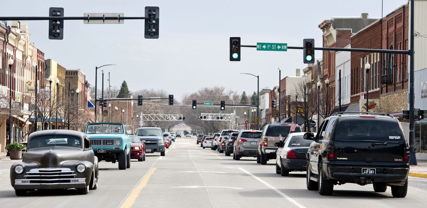 In this Sunday, April 5, 2020, photo, locals "cruise the loop" in classic cars while waving to each other and honking horns in Le Mars, Iowa. Tired of the new reality of life during the coronavirus pandemic, Le Mars residents have gone back to an old way of socializing. A popular pastime of previous generations, “Cruising the Loop,” or driving up and down Central Avenue through downtown, has returned. (Jesse Brothers/Sioux City Journal via AP)