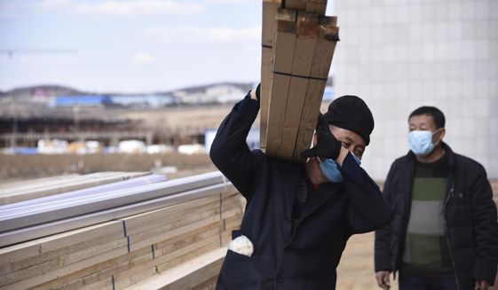 This April 10, 2020, photo released by China&#39;s Xinhua News Agency shows laborers wearing face masks to protect against the spread of the new coronavirus at an office building being converted into a temporary hospital in Suifenhe in northeastern China&#39;s Heilongjiang Province. China is facing a new coronavirus flare-up along its remote northern border with Russia, far from the epicenter of Wuhan where it has all but declared victory in the battle against the pandemic. The northern frontier has been sealed and emergency medical units were rushed to the area to fend off the threat from people bringing the virus back from abroad. (Dong Baosen/Xinhua via AP)