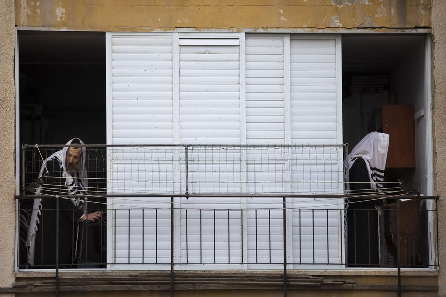 Ultra-Orthodox Jews pray a morning prayer at their house as synagogues are closed following the government's measures to help stop the spread of the coronavirus, in Bnei Brak, Israel, Tuesday, April 14, 2020. Israeli Prime Minister Benjamin Netanyahu announced Monday a complete lockdown till the end of Passover holiday to control the country's coronavirus outbreak. (AP Photo/Oded Balilty)