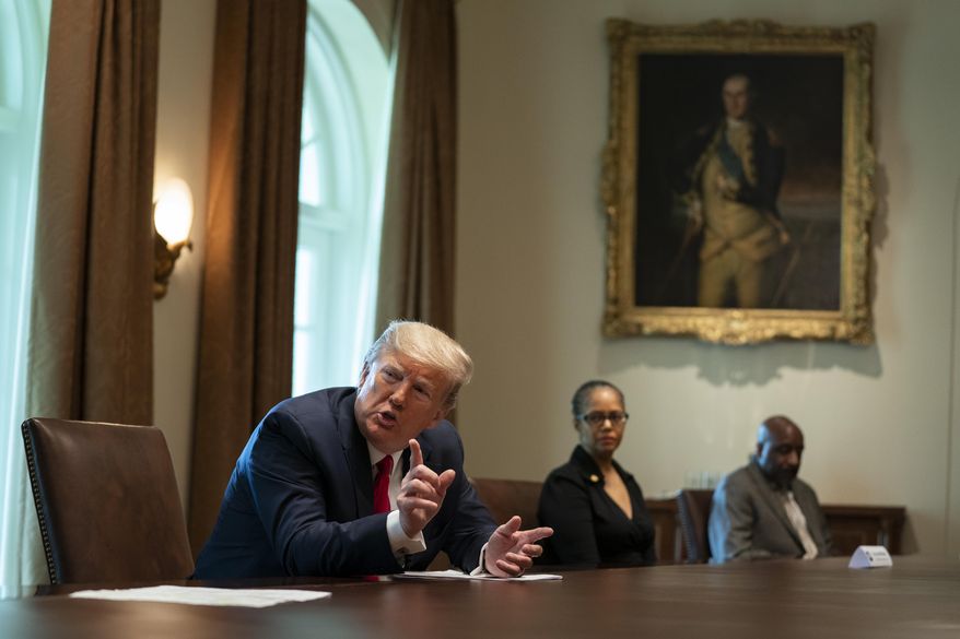 Michigan state Rep. Karen Whitsett, center, and her husband Jason Whitsett, right, listen as President Donald Trump speaks during a meeting with people that have recovered from COVID-19, in the Cabinet Room of the White House, Tuesday, April 14, 2020, in Washington. (AP Photo/Evan Vucci)