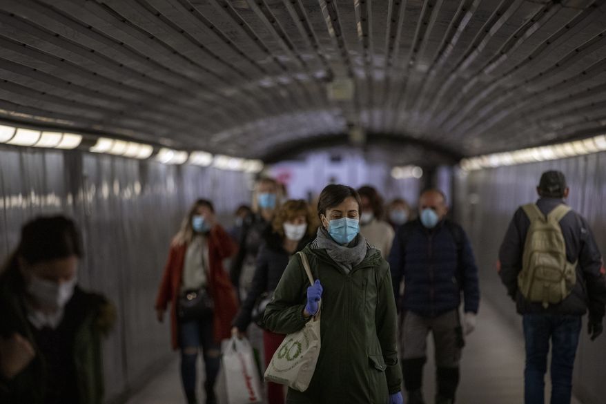 Passengers wearing face masks to prevent the spread of coronavirus, walk along a tunnel in a metro station in Barcelona, Spain, Wednesday, April 15, 2020. Spain has eased this week the conditions of Europe's strictest lockdown, allowing manufacturing, construction and other nonessential activity in an attempt to cushion the economic impact of the pandemic. (AP Photo/Emilio Morenatti)