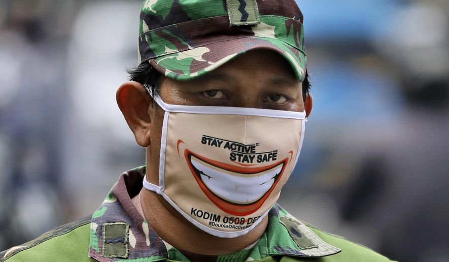 An Indonesian soldier wears face mask as he and his team man a checkpoint during the large-scale restriction imposed by the local government to curb the spread of the coronavirus outbreak in Jakarta, Indonesia, Wednesday, April 15, 2020. Indonesia's capital kicked off the stricter restriction last week as the metropolitan area has become Indonesia's coronavirus epicenter. (AP Photo/Dita Alangkara)