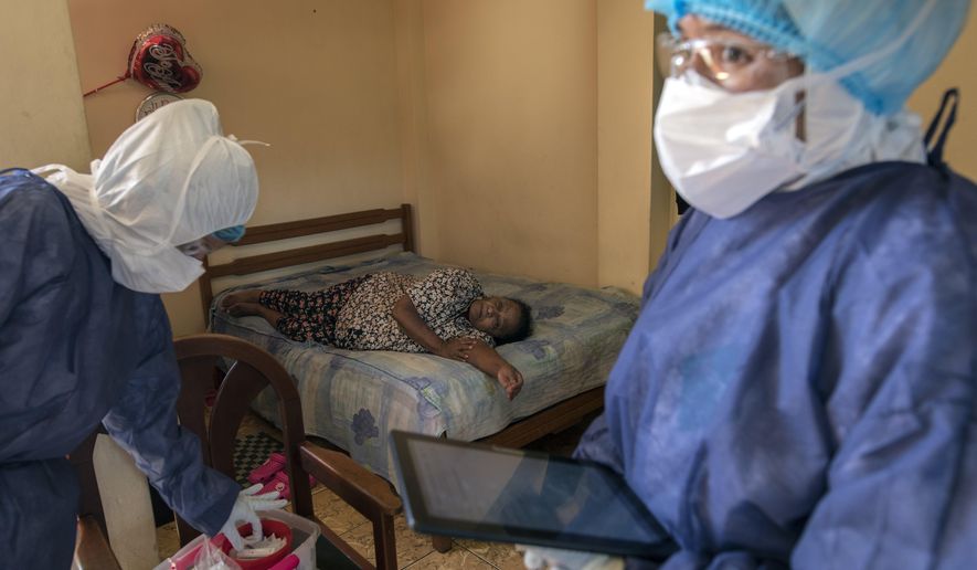 Maria Teresa Carrillo, 87, rests in a bed as Doctor Leslei Montoro, left, and her colleague Doctor Carolina Quiroz, check a sample for a new coronavirus fast test, in Lima, Peru, Wednesday, April 15, 2020. Peruvians can call a telephone number to report that they have COVID-19 symptoms and the state organized medical brigades will visit and do rapid tests to confirm or rule out new infections. (AP Photo/Rodrigo Abd)
