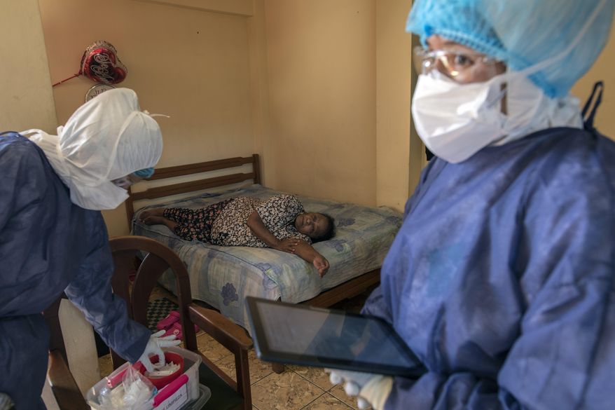 Maria Teresa Carrillo, 87, rests in a bed as Doctor Leslei Montoro, left, and her colleague Doctor Carolina Quiroz, check a sample for a new coronavirus fast test, in Lima, Peru, Wednesday, April 15, 2020. Peruvians can call a telephone number to report that they have COVID-19 symptoms and the state organized medical brigades will visit and do rapid tests to confirm or rule out new infections. (AP Photo/Rodrigo Abd)