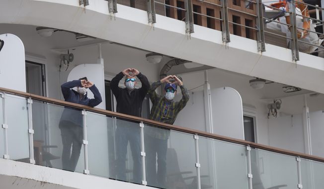 Passengers on the Australian cruise ship name Greg Mortimer gesture heart signs as they arrive to port on their way to the international airport in Montevideo, Uruguay, Wednesday, April 15, 2020. The ship has been anchored off Uruguay&#x27;s coast since March 27 with more than half its passengers and crew infected with the new coronavirus, according to authorities. (AP Photo/Matilde Campodonico)