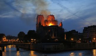 FILE - In this April 15, 2019, file photo, firefighters tackle the blaze as flames and smoke rise from Notre Dame cathedral in Paris. The cathedral stands crippled, locked in a dangerous web of twisted metal scaffolding one year after a cataclysmic fire gutted its interior, toppled its famous spire and horrified the world. (AP Photo/Michel Euler, File)