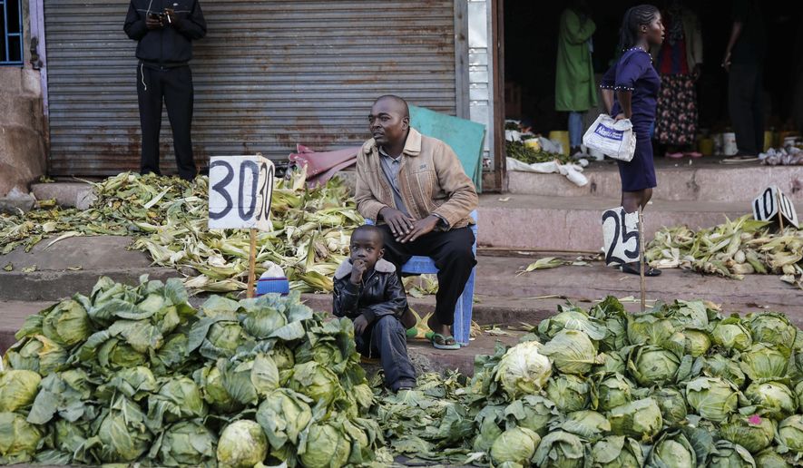 In this March 24, 2020, file photo, a street trader sells cabbages by the side of the road, after the government ordered the closure of the main open-air market, in the Mathare slum, or informal settlement, of Nairobi, Kenya. Lockdowns in Africa limiting the movement of people in an attempt to slow the spread of the coronavirus are threatening to choke off supplies of what the continent needs the most: Food. (AP Photo/Brian Inganga, File)