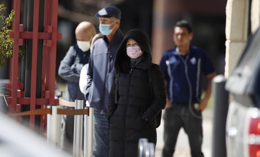Practicing social distancing, customers wearing masks during the coronavirus pandemic while waiting to enter a Wells Fargo Bank branch Tuesday, April 14, 2020, in Aurora, Colo. The new coronavirus causes mild or moderate symptoms for most people, but for some, especially older adults and people with existing health problems, it can cause more severe illness or death. (AP Photo/David Zalubowski)