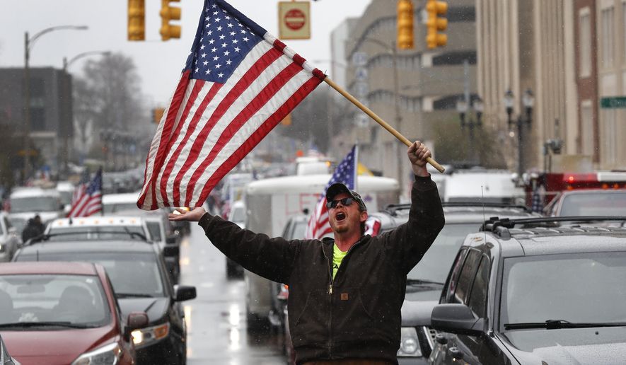 Christopher Merrill protests at the State Capitol in Lansing, Mich., Wednesday, April 15, 2020. Flag-waving, honking protesters drove past the Michigan Capitol on Wednesday to show their displeasure with Gov. Gretchen Whitmer&#39;s orders to keep people at home and businesses locked during the new coronavirus COVID-19 outbreak. (AP Photo/Paul Sancya)