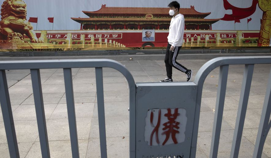 A resident wearing a mask against coronavirus walks past government propaganda poster featuring Tiananmen Gate in Wuhan in central China&#39;s Hubei province Thursday, April 16, 2020.  (AP Photo/Ng Han Guan)