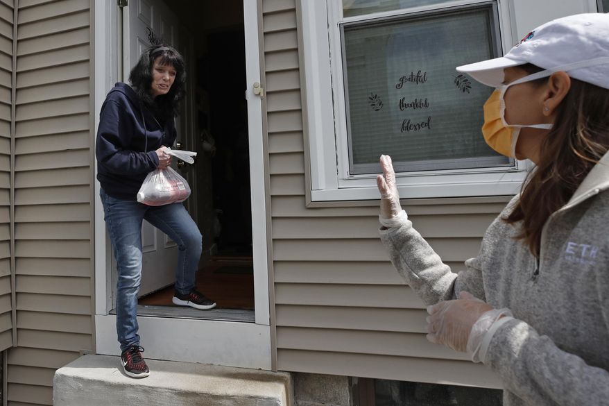 In this April 15, 2020 photo, Neighbors in Need volunteer Julie Prentiss, right, delivers groceries to a client, Wendy, in Lawrence, Mass. During the coronavirus pandemic, NIN is providing food for about 600 families each week. (AP Photo/Elise Amendola)