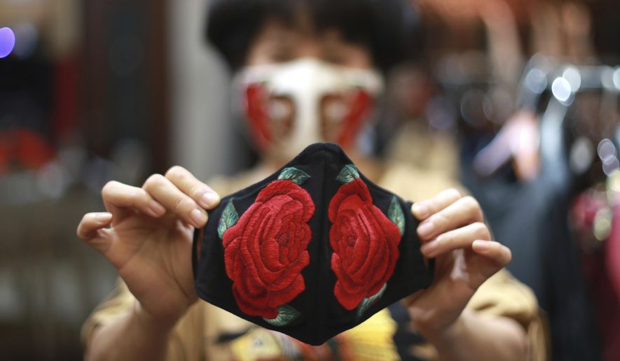In this Wednesday, April 15, 2020, photo, fashion designer Do Quyen Hoa shows off an embroidery face mask at her studio in Hanoi, Vietnam. The collection of face masks adorned with Vietnamese hand embroideries was created as the world is fighting against the spread of the new coronavirus. (AP Photo/Hau Dinh)