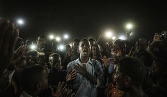 This image released by World Press Photo on Thursday April 16, 2020, taken by Yasuyoshi Chiba, Agence France-Presse, won the World Press Photo of the Year award, and the first prize in the General News Singles category, a young man, illuminated by mobile phones, recites protest poetry while demonstrators chant slogans calling for civilian rule, during a blackout in Khartoum, Sudan, on 19 June 2019. (Yasuyoshi Chiba, Agence France-Presse/World Press Photo via AP)