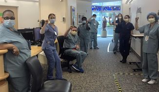 In this image provided by Lizabeth Baker Wade, nurses at Providence Saint John&#39;s Health Center in Santa Monica, Calif., on April 10, 2020, raise their fists in solidarity after telling managers they can&#39;t care for COVID-19 patients without N95 respirator masks to protect themselves. The hospital has suspended ten nurses from the ward, but has started providing nurses caring for COVID-19 patients with N95 masks. (Lizabeth Baker Wade via AP)