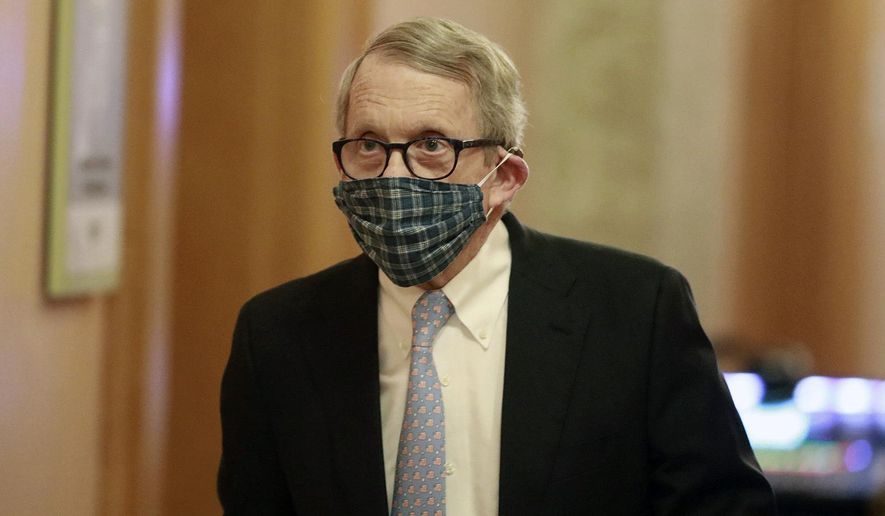 Wearing his protective mask made by his wife, Ohio Gov. Mike DeWine walks into his daily coronavirus news conference on Thursday, April 16, 2020, at the Ohio Statehouse in Columbus, Ohio. (Doral Chenoweth/The Columbus Dispatch via AP) ** FILE **