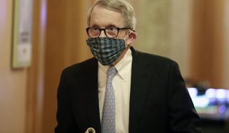 Wearing his protective mask made by his wife, Ohio Gov. Mike DeWine walks into his daily coronavirus news conference on Thursday, April 16, 2020, at the Ohio Statehouse in Columbus, Ohio. (Doral Chenoweth/The Columbus Dispatch via AP)