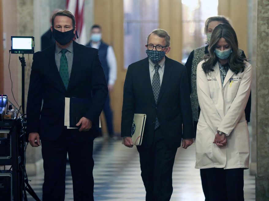 Wearing their protective masks, from left, Ohio Lt. Gov. Jon Husted, Gov. Mike DeWine, and Ohio Department of Health Director Dr. Amy Acton walk into their daily coronavirus news conference Wednesday, April 15, 2020 at the Ohio Statehouse in Columbus, Ohio. (Doral Chenoweth/The Columbus Dispatch via AP)