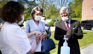 Belgium's King Philippe, right, and Queen Mathilde, center, wear mouth masks and use hand gel as they visit the Regional Hospital Center in Liege, Belgium, during the outbreak of the COVID-19 virus, Friday, April 17, 2020. While supermarkets and pharmacies remain open Belgium continues to be on partial lockdown to prevent the spread of the coronavirus. (Daina Le Hardic, Pool Photo via AP)
