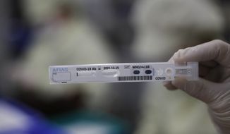 An employee holds up an antibody test cartridge of AFIAS COVID-19 Ab testing kit used in diagnosing the coronavirus for a photograph on a production line of the Boditech Med Inc. in Chuncheon, South Korea, Friday, April 17, 2020. (AP Photo/Lee Jin-man)