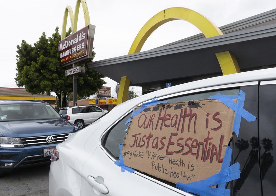 FILE - In this April 6, 2020, file photo, protesters stop momentarily at a McDonald's drive-thru, as they join fast-food workers protesting for a second day outside the restaurant in the Crenshaw district of Los Angeles. The protesters were demanding guaranteed paid sick leave for all workers during the coronavirus outbreak, as well as personal protection equipment, after a co-worker became sick with the virus. Farm workers, grocery store and fast-food employees and delivery drivers will receive two weeks of paid sick leave so they won’t feel pressured to keep working while infected with the coronavirus, California Gov. Gavin Newsom announced. The executive order signed Thursday, April 16, covers those who work for large employers, filling a gap left by a federal act this month that required employers to provide emergency paid sick leave but exempted those with more than 500 workers. (AP Photo/Damian Dovarganes, File)