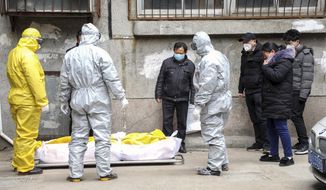 Funeral home workers remove the body of a person suspected to have died from the coronavirus outbreak from a residential building in Wuhan in central China&#39;s Hubei Province,&quot; Feb 1, 2020. The central Chinese city of Wuhan has raised its number of COVID-19 fatalities by more than 1,000. State media said the undercount had been due to the insufficient admission capabilities at overwhelmed medical facilities at the peak of the outbreak. (Chinatopix via AP) ** FILE ** 
