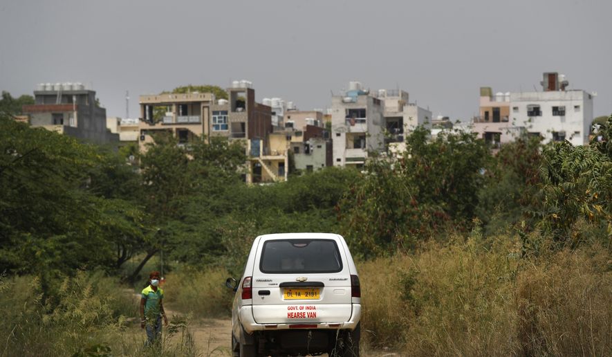 In this Thursday, April 16, 2020, photo, a government hearse van arrives at a cemetery carrying the body of a 52-year-old woman who died of COVID-19 in New Delhi, India. Of all the devastating consequences the coronavirus pandemic has brought to the world, the most painful may well be the lonely burials. It has forced a change in the way those left behind are mourning their dead, upending rituals carried out from generations. The deceased are not allowed a final hug from their loved ones to say farewell. And sometimes, they don’t even get a proper burial. (AP Photo/Manish Swarup)