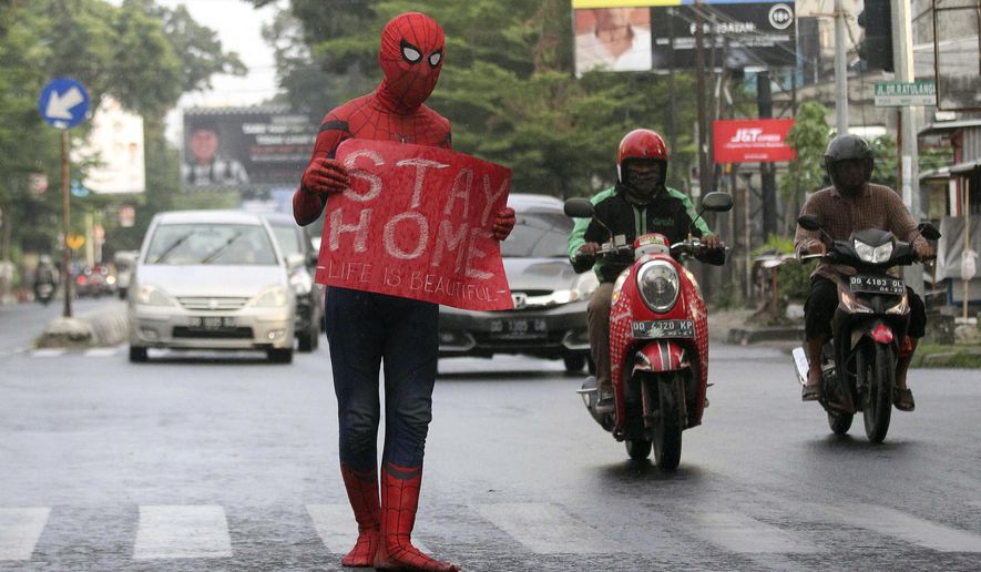 A man wearing a Spiderman costume holds a poster during a campaign to create awareness about coronavirus outbreak in Makassar, South Sulawesi, Indonesia, Friday, April 17, 2020. (AP Photo/Masyudi S. Firmansyah)