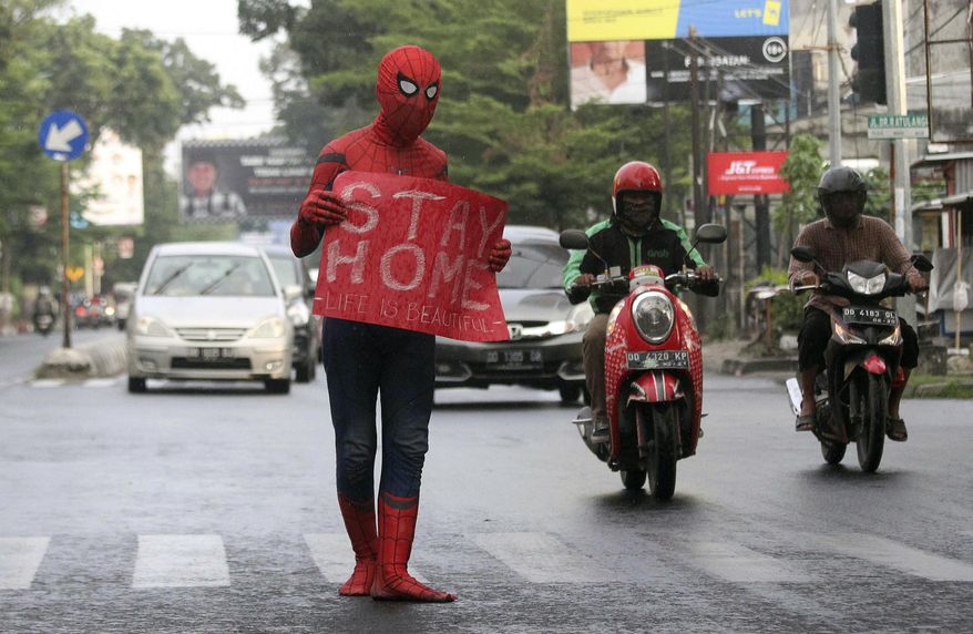 A man wearing a Spiderman costume holds a poster during a campaign to create awareness about coronavirus outbreak in Makassar, South Sulawesi, Indonesia, Friday, April 17, 2020. (AP Photo/Masyudi S. Firmansyah)