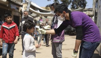 A member of a non-governmental aid organization measures temperature as a preventive measure for coronavirus in the town of Kafr Takharim, Idlib province, Syria, Tuesday, April 14, 2020. (AP Photo/Ghaith Alsayed)