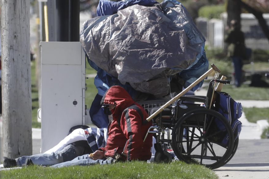 A man sits near a sidewalk Tuesday, April 14, 2020, in Salt Lake City. Salt Lake City is leasing a hotel to shelter homeless people over 60 with underlying health conditions who are particularly vulnerable to coronavirus infections. People began checking into the 130-bed hotel Friday and can stay for at least two weeks with a possible extension, said county Mayor Jenny Wilson. Salt Lake City has confirmed a handful of cases in the homeless community, where preventative steps such as hand-washing and social distancing are more difficult. (AP Photo/Rick Bowmer)