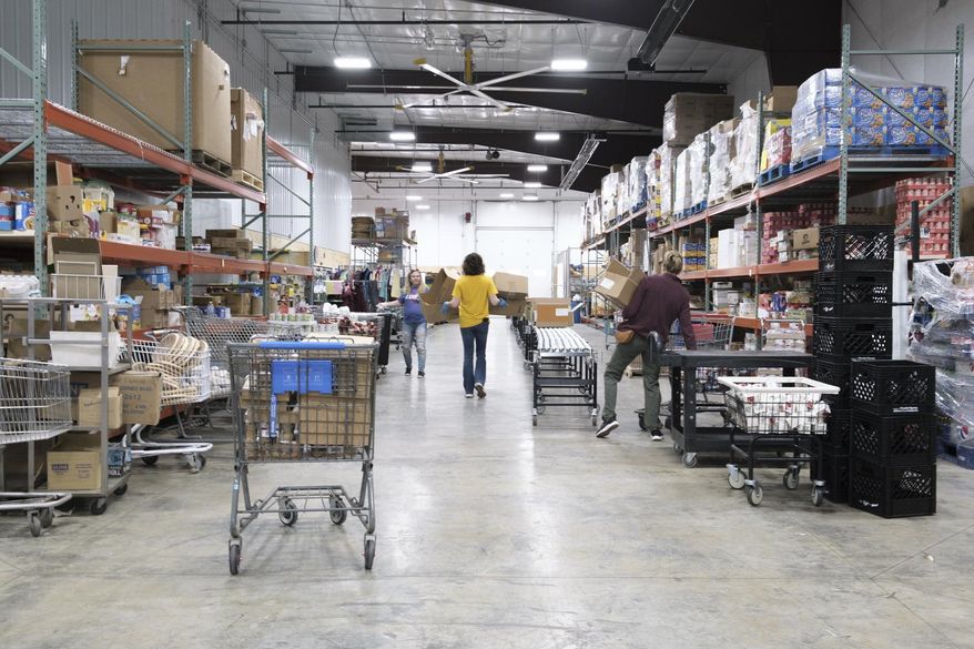 Volunteers and staff pack and drop off food for clients on Tuesday , March 31, 2020 at Northeast Community Fund in Decatur. A new drive-through service is being offered to limit interaction with clients while still providing the needed service.(Jeff Smudde/Herald & Review via AP)