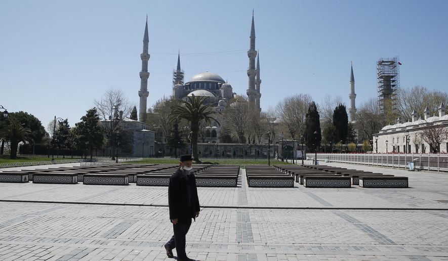 A man walks in a deserted place near the Blue Mosque, one of the city's landmarks, in Istanbul, Saturday, April 18, 2020, hours after the start of a two-day curfew declared by the government in an attempt to control the spread of coronavirus. (AP Photo/Mehmet Guzel)