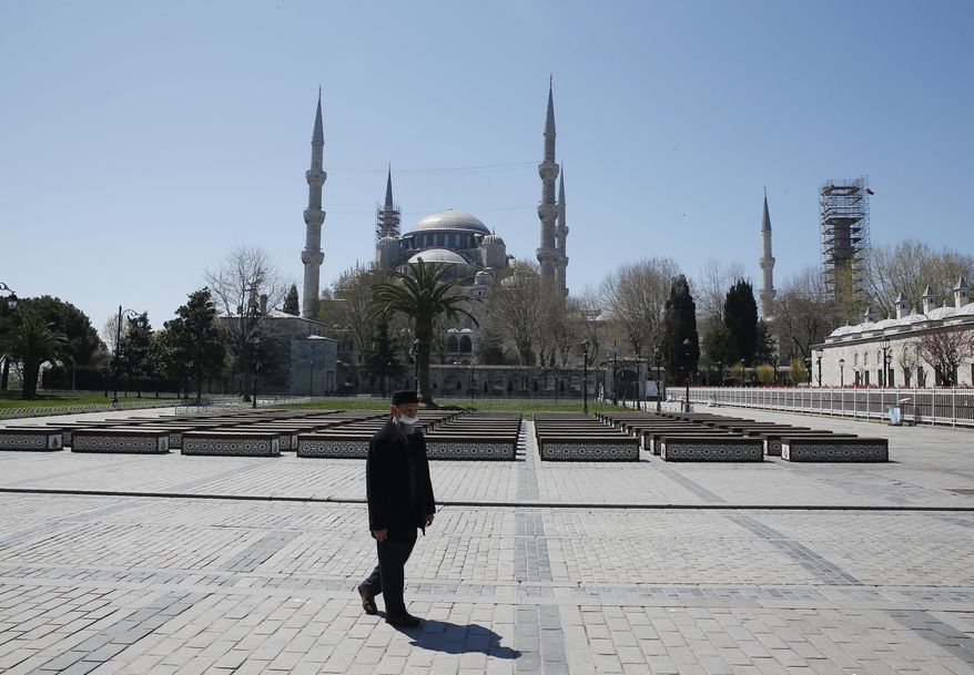 A man walks in a deserted place near the Blue Mosque, one of the city's landmarks, in Istanbul, Saturday, April 18, 2020, hours after the start of a two-day curfew declared by the government in an attempt to control the spread of coronavirus. (AP Photo/Mehmet Guzel)
