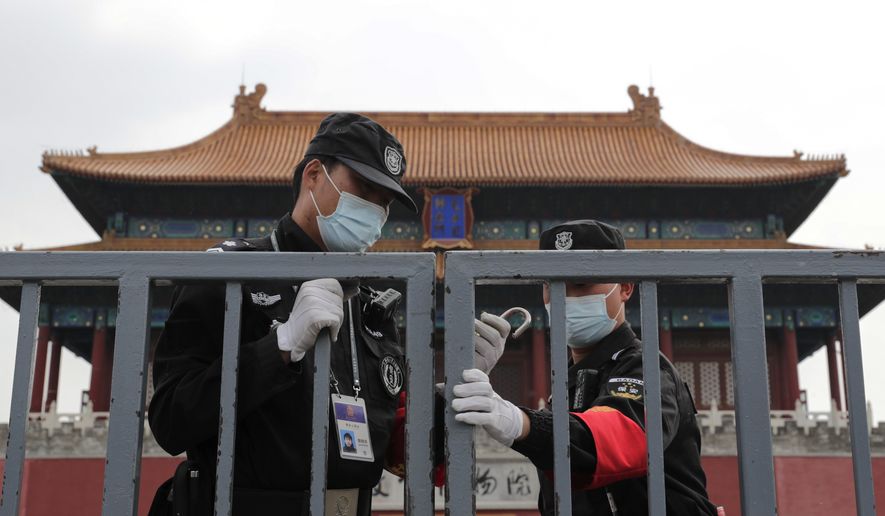 Security guards wearing protective face masks to prevent the spread of the new coronavirus lock the gate of the Forbidden City which remains closed following the new coronavirus outbreak in Beijing, Sunday, April 19, 2020. The pandemic that began in China in December is believed to have infected more than 2 million people worldwide. While most recover, at least over 150,000 have died, according to a tally by Johns Hopkins University based on figures supplied by health authorities around the globe. (AP Photo/Andy Wong)