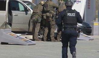 Royal Canadian Mounted Police officers prepare to take a suspect into custody at a gas station in Enfield, Nova Scotia on Sunday April 19, 2020. Canadian police  arrested a suspect in an active shooter investigation after earlier saying he may have been driving a vehicle resembling a police car and wearing a police uniform.  (Tim Krochak/The Canadian Press via AP)